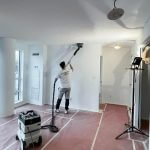 painter doing popcorn ceiling removal in a house using dustless sanding equipment