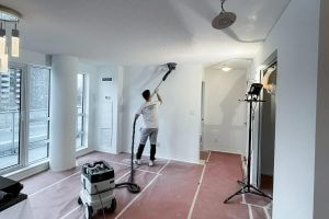 painter doing popcorn ceiling removal in a house using dustless sanding equipment